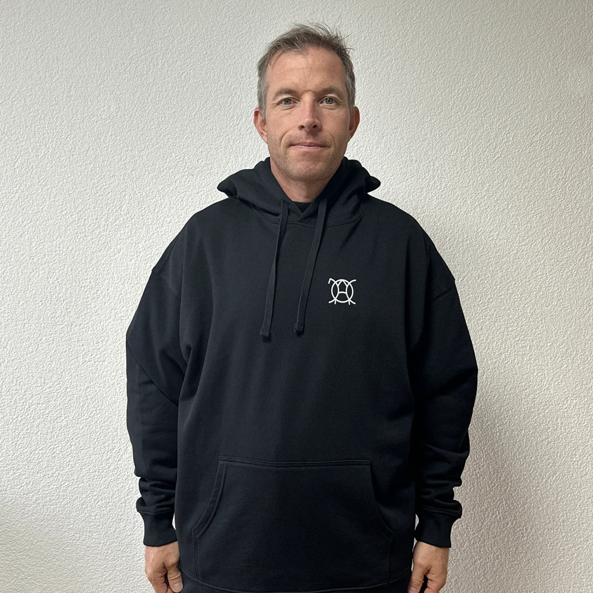 Hoodie Rebuild & Rebirth noir porté par Benoît, fondateur de JaOcCo, coupe oversize taille M, vue de face